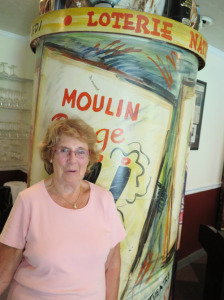 Pierrette Baldwin, who turns 80 in September, next to the vintage, atmospheric Chez Pierre decor created by Glens Falls artist Tom Mahoney.