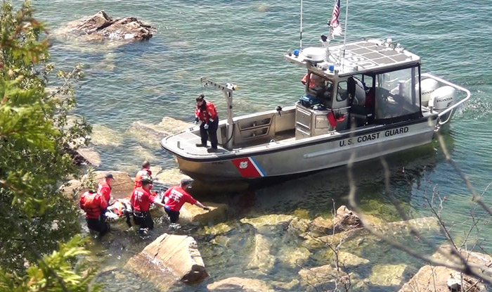 Colchester Technical Rescue carefully lift a woman onto the deck of a U.S. Coast Guard boat from Burlington after she was discovered, fallen from the Rock Point cliffs and spending the night injured on the shores of Lake Champlain.